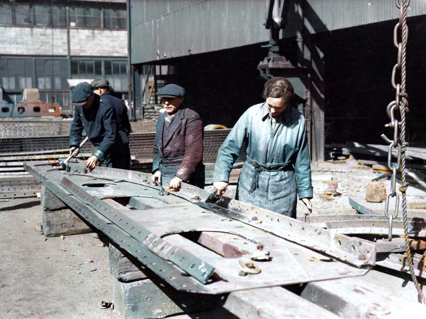 Two men and woman working at the Caledon Shipyard in 1944, working outdoors on a large sheet of metal