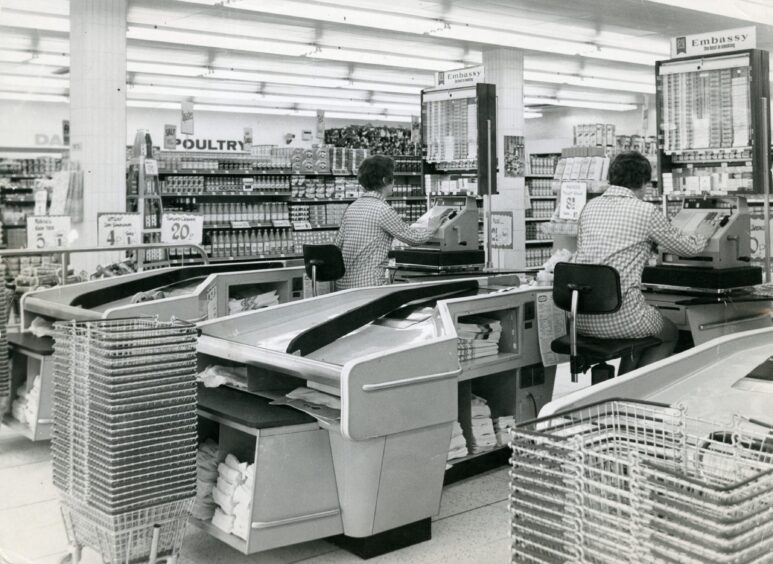 two women seated at the checkout tills in the 1970s