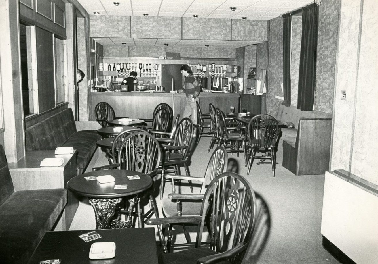 a man stands beside the bar holding a queue at the snooker club