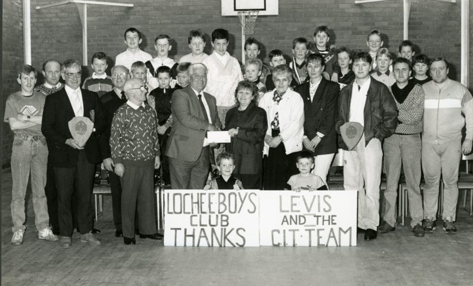 Officials and children as Charles Farquhar collects the cheque from Margaret Dodds at Lochee Boys Club