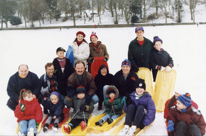 A group of people pose for a picture while sledging in the snow at Lochee Park in December 1993.