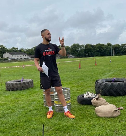 Rhys Spackman in black shorts and shirt standing in front of tractor tyres