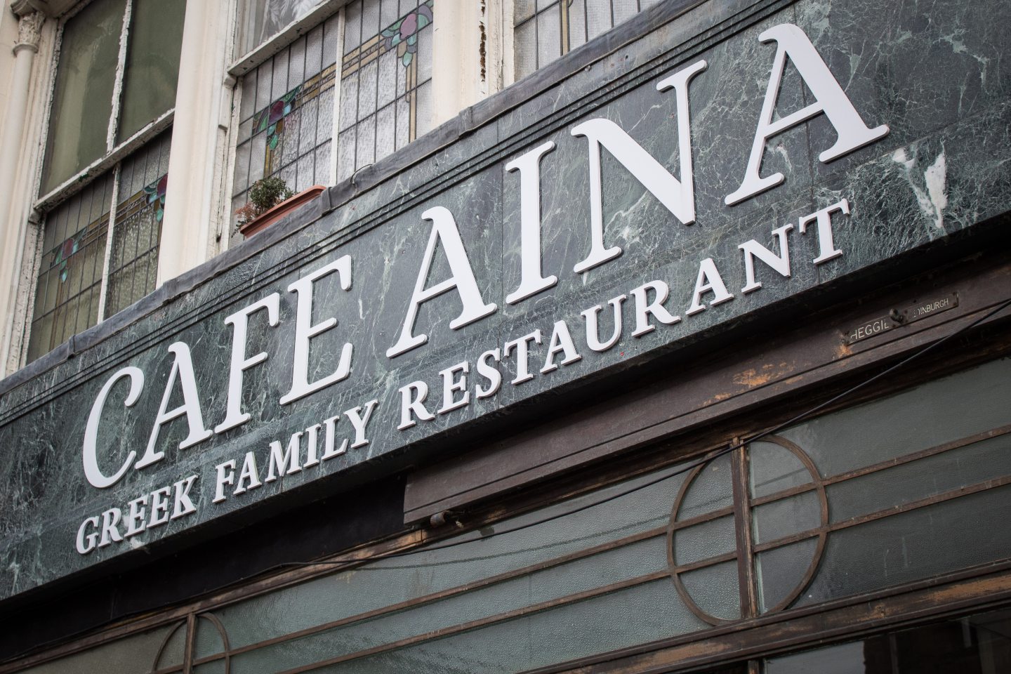 Sign reading 'Cafe Aina: Greek Family Restaurant' 