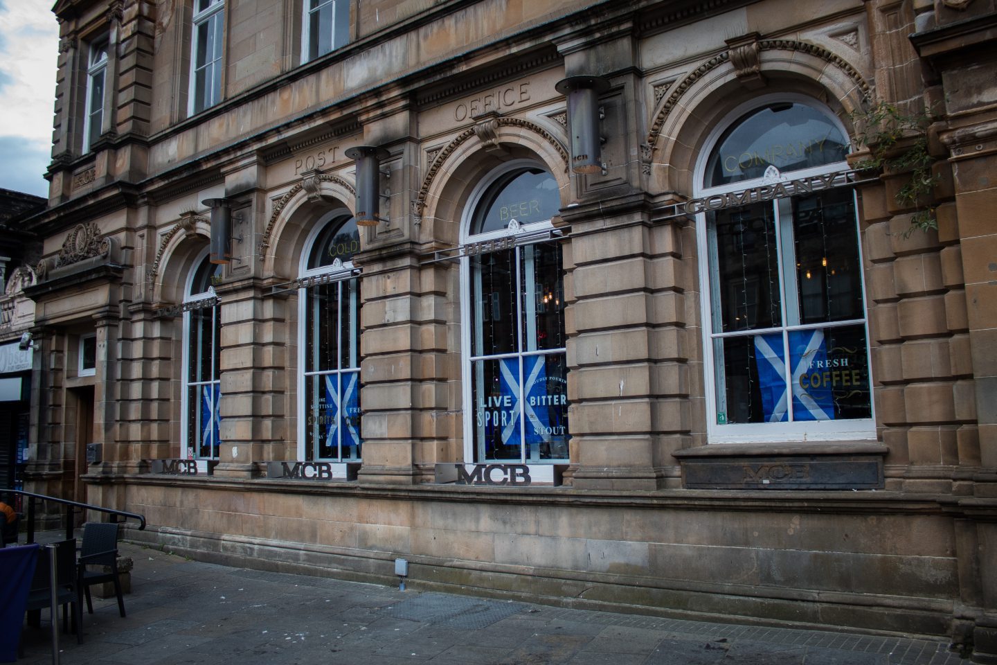 Building with tall windows and signs reading "MCB"