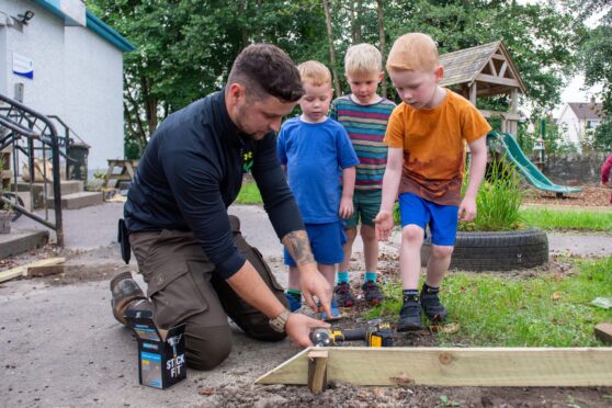 Connor Park on his knees working in outdoor classroom helped by three small boys