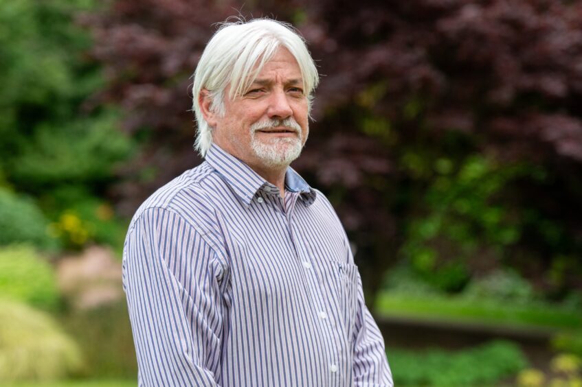 Grant Laing portrait with trees and greenery behind.