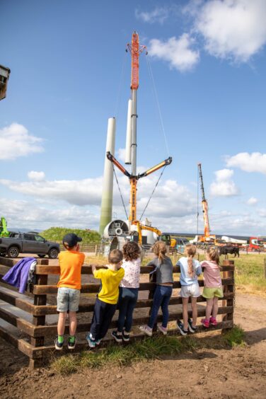 Small children watching wind turbine tower being constructed