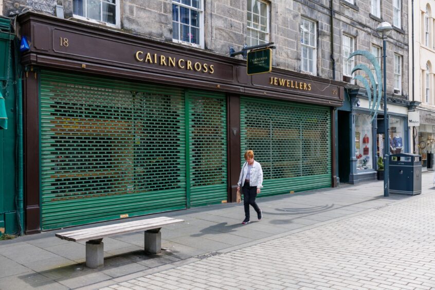 Woman walking past shuttered Cairncross jewellers shop in Perth