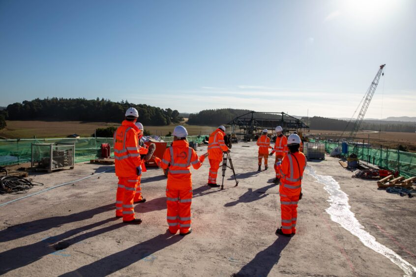 People in hi vis gear at Destiny Bridge with Cross Tay liny road stretching to horizon