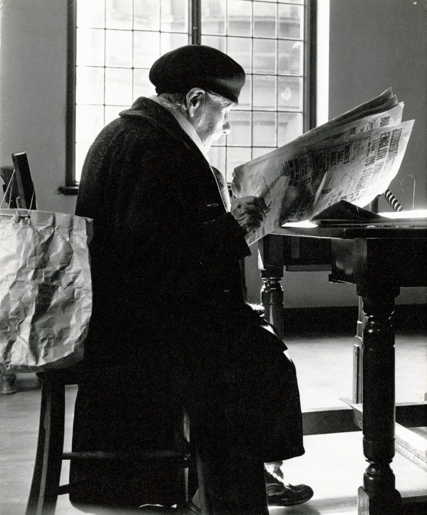 A lady looks at a newspaper in the Ward Road Library reading room. 