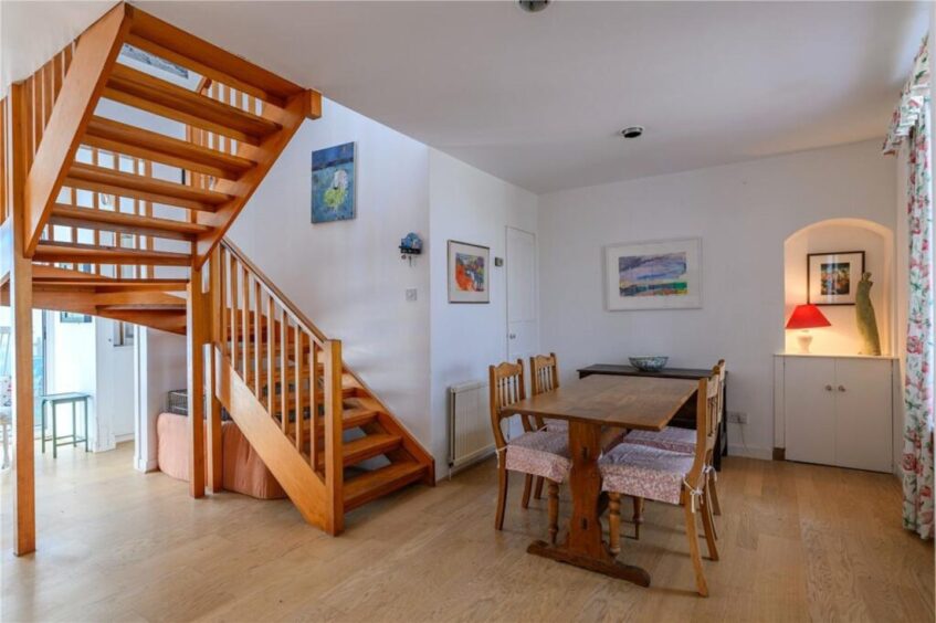 A wooden staircase leads to the first floor. 