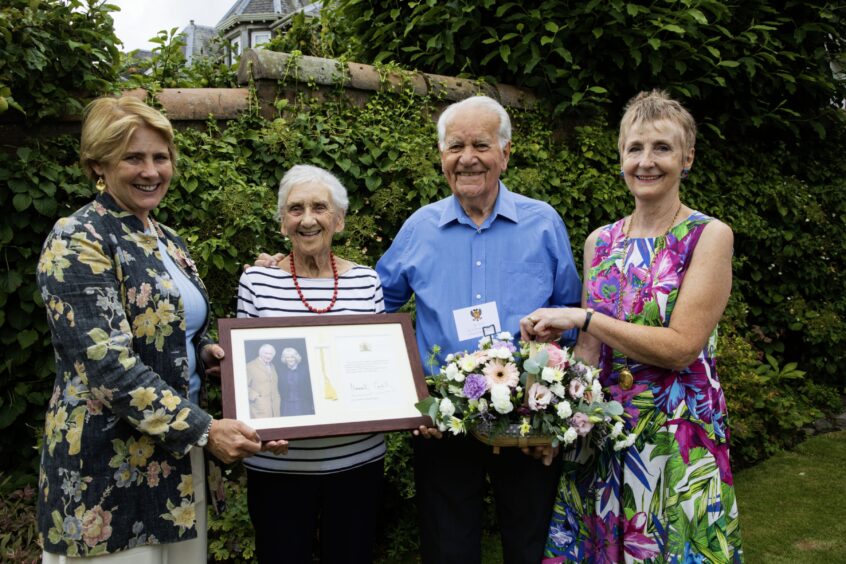 Eddie and Mabel Hartley smiling in garden with Deputy Lord Lieutenant Catherine Drummond-Herdman and Councillor Liz Barrett.