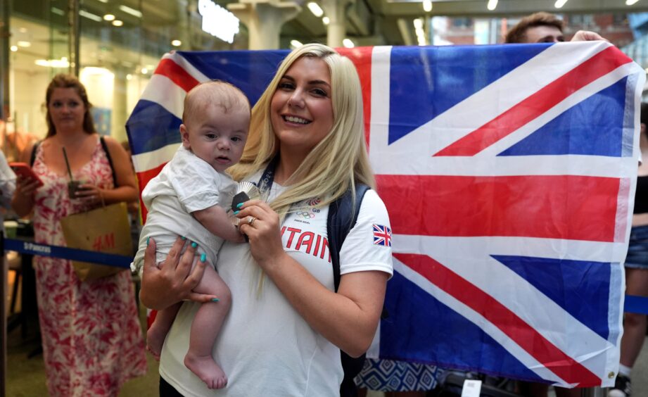 Great Britain's Amber Rutter with son Tommy and her silver medal from the women's skeet shooting after they arrived back in London. 