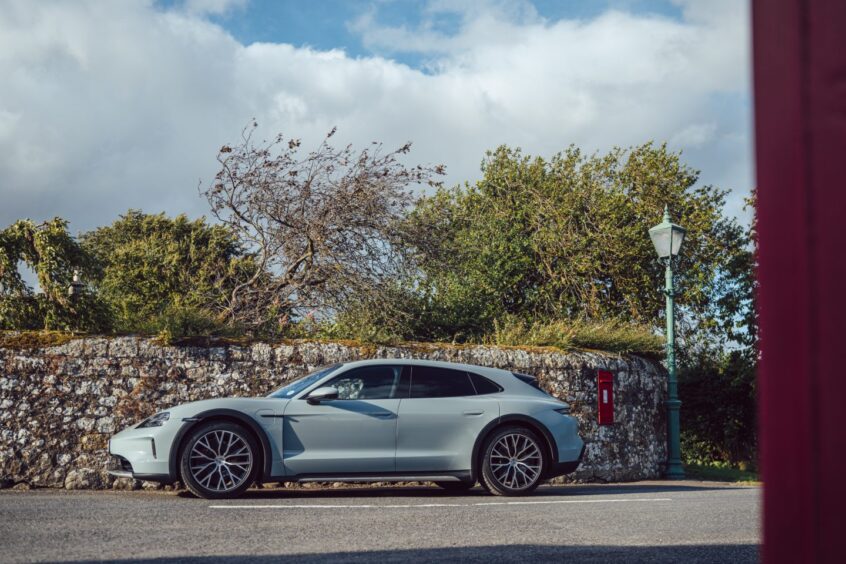 The Taycan parked beside a stone wall