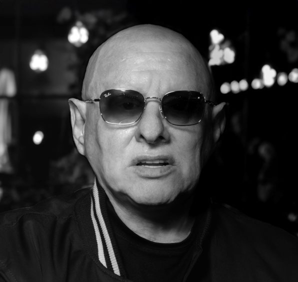 A head and shoulders shot of a shaven-headed Shaun Ryder wearing sunglasses.