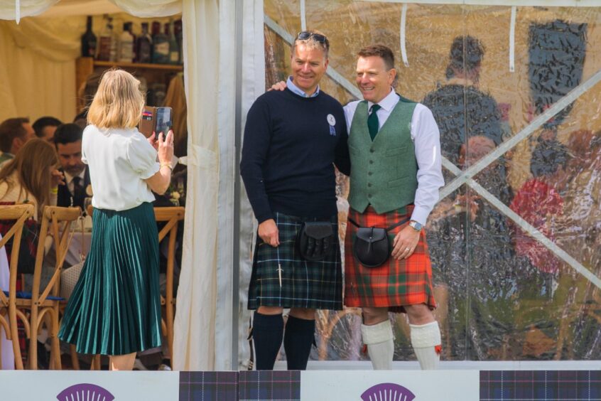 Ewan Mc Gregor and brother in kilts posing for photo outside hospitality tent at Crieff Highland Gathering
