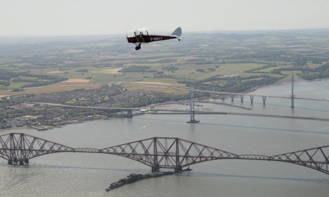 A Tiger Moth aircraft flies over the three Forth bridges. Image: BBC