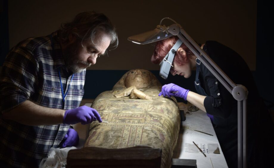 Two people examining a sarcophagus for Nile water damage