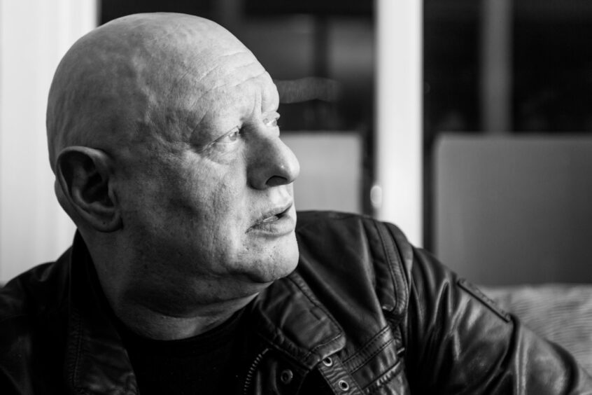 A black and white profile shot of Shaun Ryder.