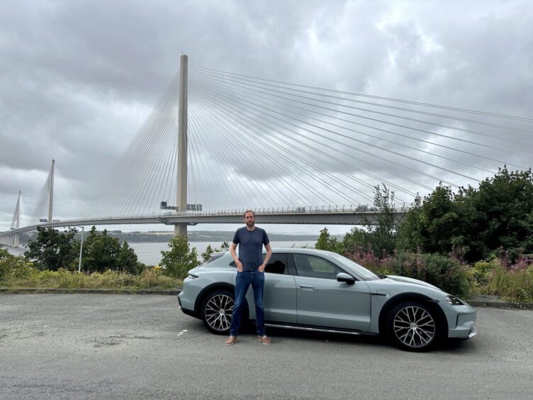 Jack McKeown stands beside the Porsche with the Queensferry Crossing in the distance