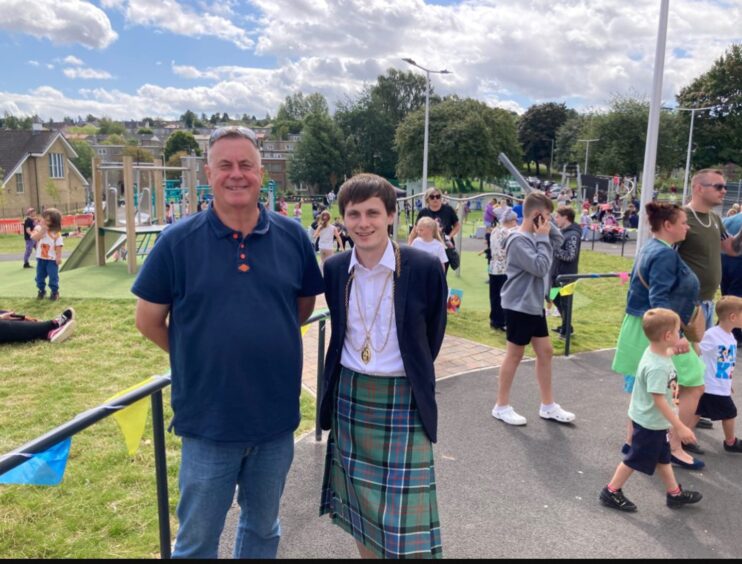 Local councillor John Rebbeck and Provost Xander McDade with large group of locals enjoying outdoors activities behind