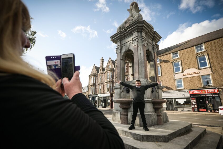 School boy getting his photograph taken next to fountain