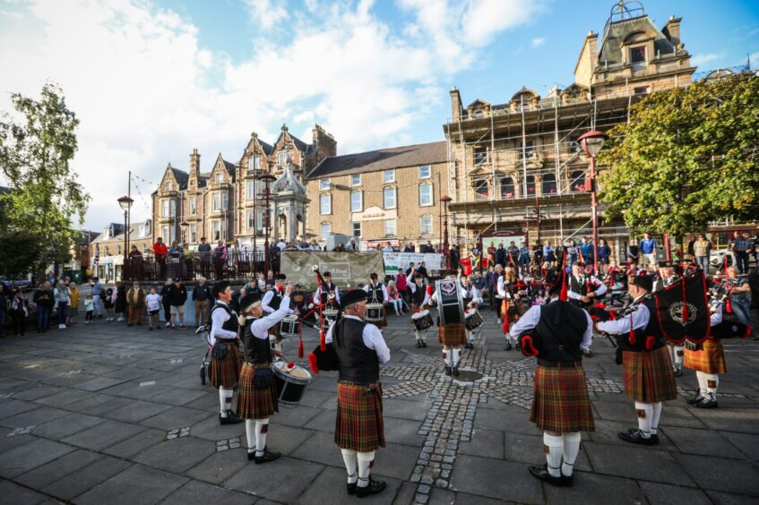 Pipe band playing in James Square Crieff, watched by large crowd