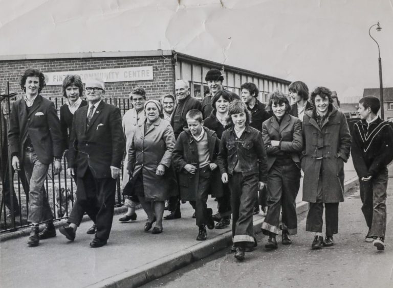 adults and youngsters walking along a pavement