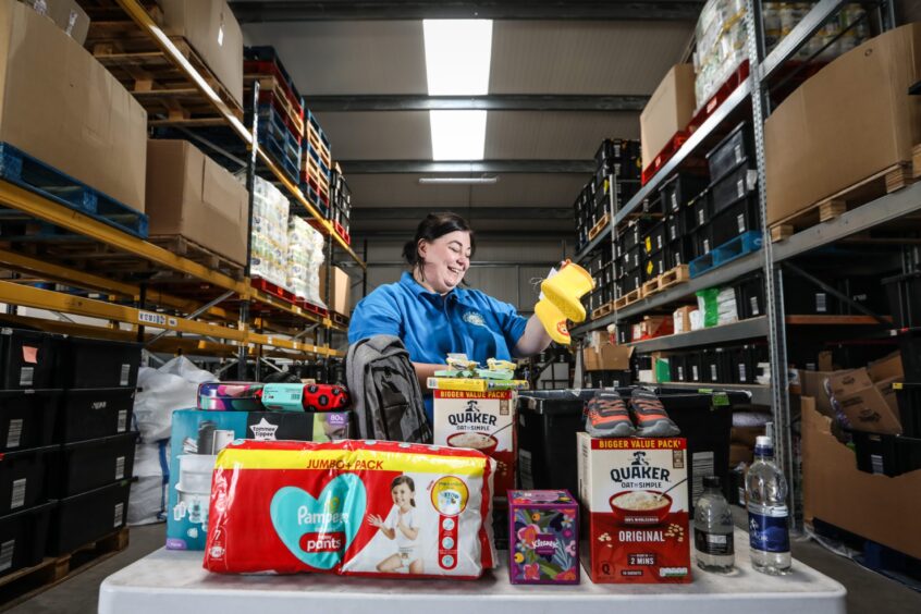 Charity manager Genna Millar in the warehouse sorting a food package.