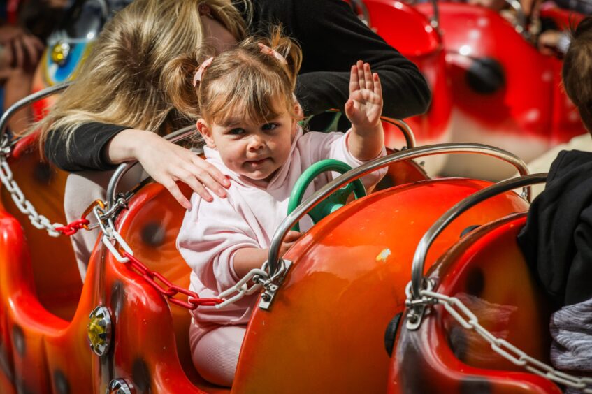 Lily Cameron, 2, waves to her mum from one of the rides at the Lammas Market in St Andrews