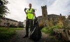 Mark Hunter has been recognised as a litter hero in Crieff. He is posing with bag and litter picker in the town.