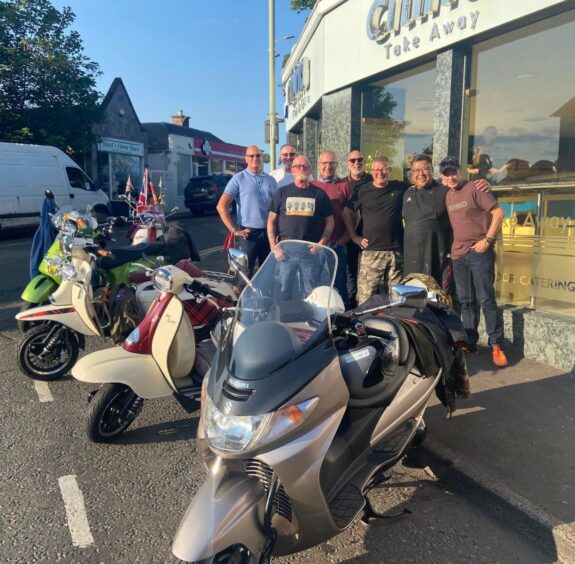 Pete Chan outside China China with a group of men with scooters parked outside