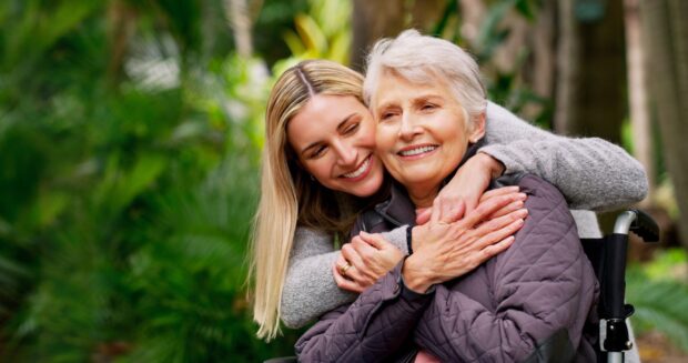 Younger woman with her arms around the older woman.