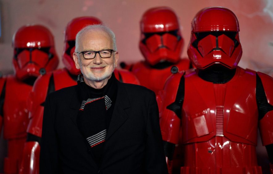 Star Wars actor Ian McDiarmid beside a row of red-armoured Storm Troops