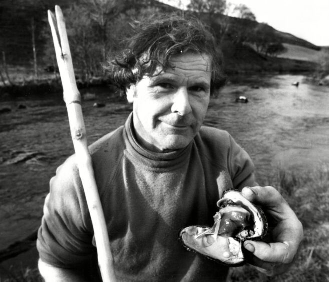 Black and white photo of Bill Abernethy holding pearl in mussel shell beside Perthshire river