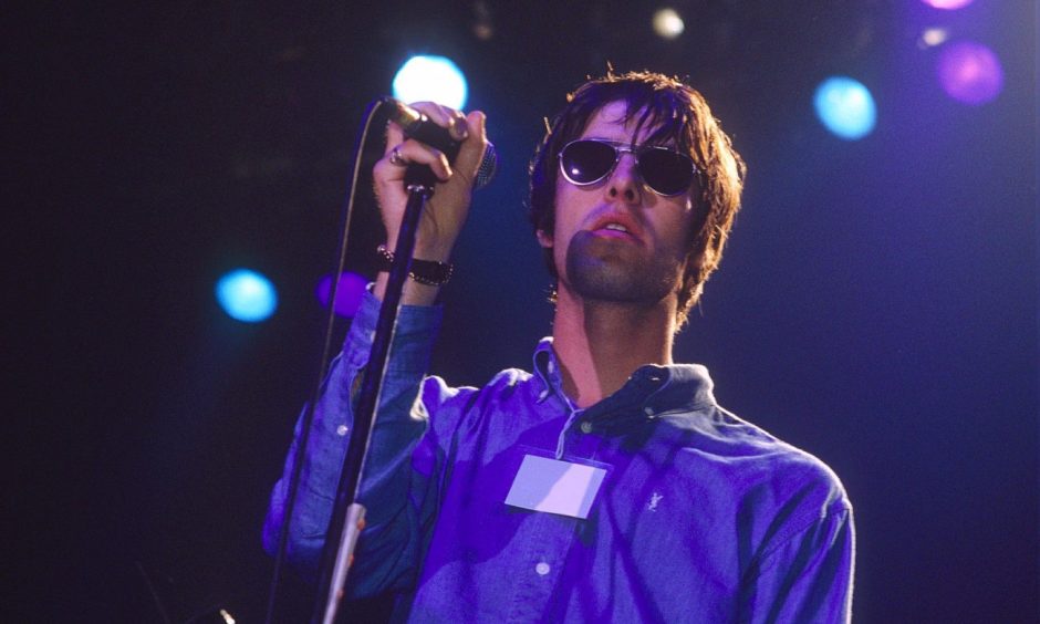 Oasis frontman Liam Gallagher holds the mic while on stage in 1994, the year Definitely Maybe was released