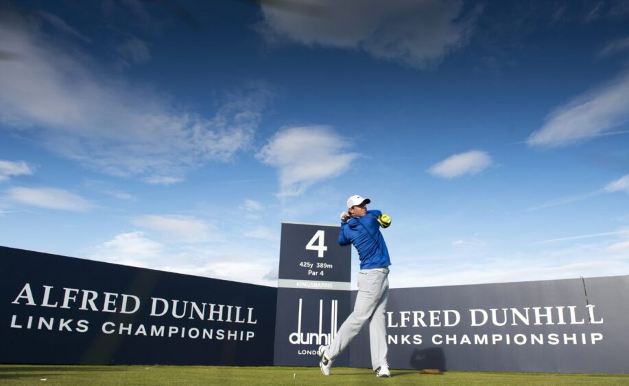 Rory McIlroy tees off in front of signs stating Alfred Dunhill Links Champonship