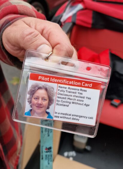 Hand holding Cycling Without Age Scotland Pilot Identification card with photo of Rowen Ross