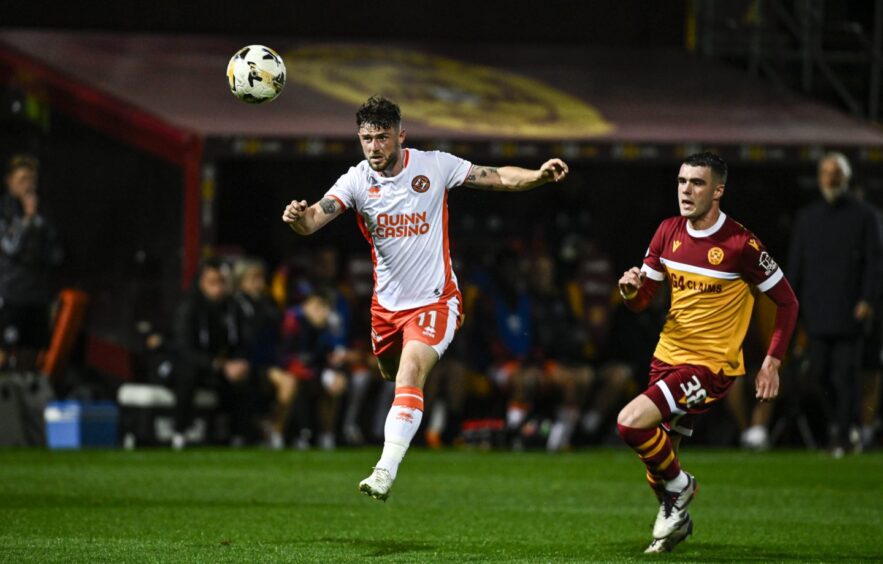 Dundee United defender Will Ferry makes a thundering clearing header against Motherwell