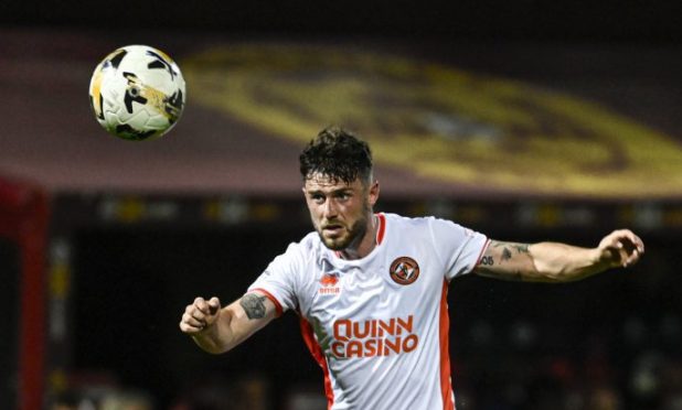 Dundee United defender Will Ferry makes a thundering clearing header against Motherwell