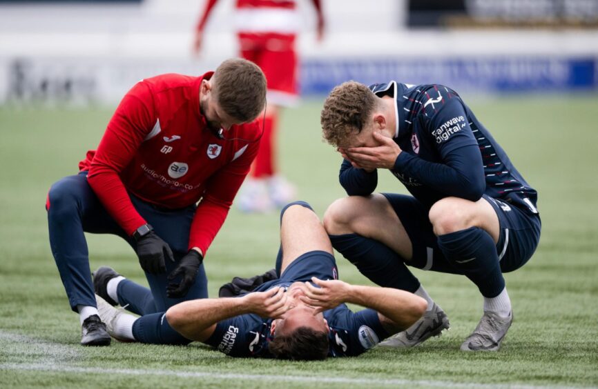 Jack Hamilton crouches down as Lewis Vaughan receives treatment for an injury against Hamilton.