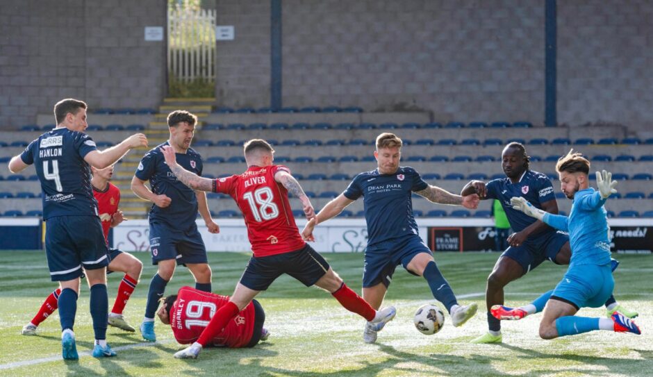 The Raith and Falkirk players battle for possession inside a crowded penalty box.