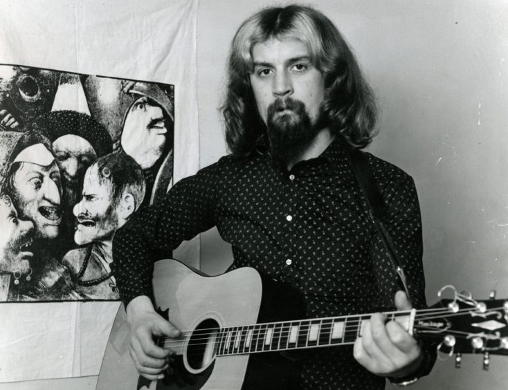 a young Billy Connolly holding a guitar