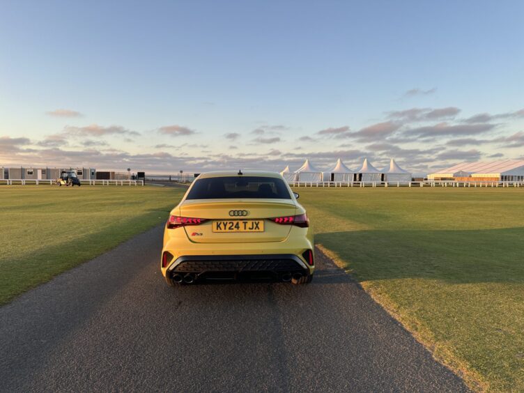 the car seen from the rear, with the golf course in the background