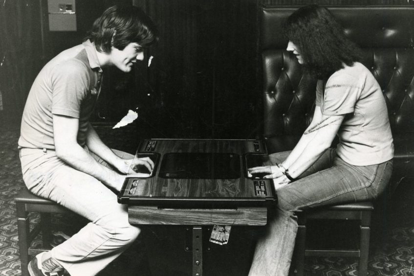 A table electronic game keeps two people amused. 