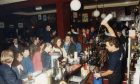 A barman pours a drink as people queue at the bar in a cocktail night at The Bread on Constitution Road in November 1990