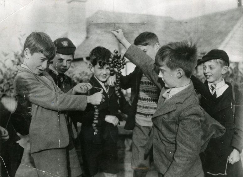 two boys play conkers while other boys look on in a Dundee street