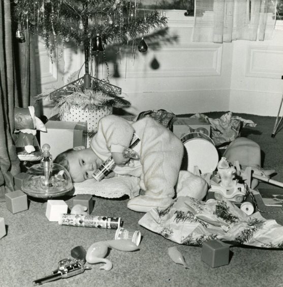 a toddler lying amid a pile of Christmas gifts and wrapping paper