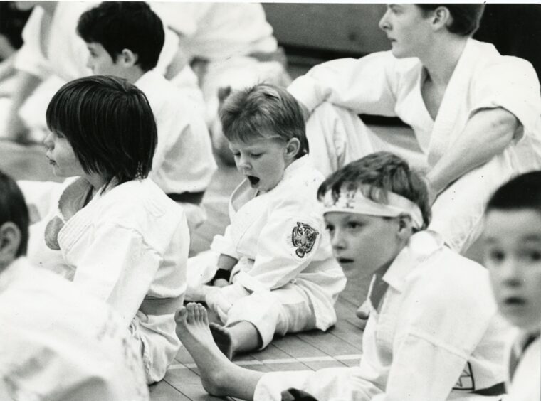 Young boys sit on the floor at the full contact karate workshop. 