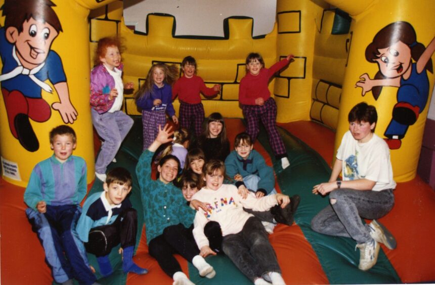 children play on a bouncy castle in a Dundee community centre